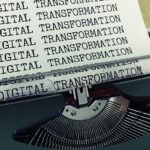 Eine Schreibmaschine, aus der ein Blatt Papier herauskommt, auf dem „Digital Transformation“ steht.