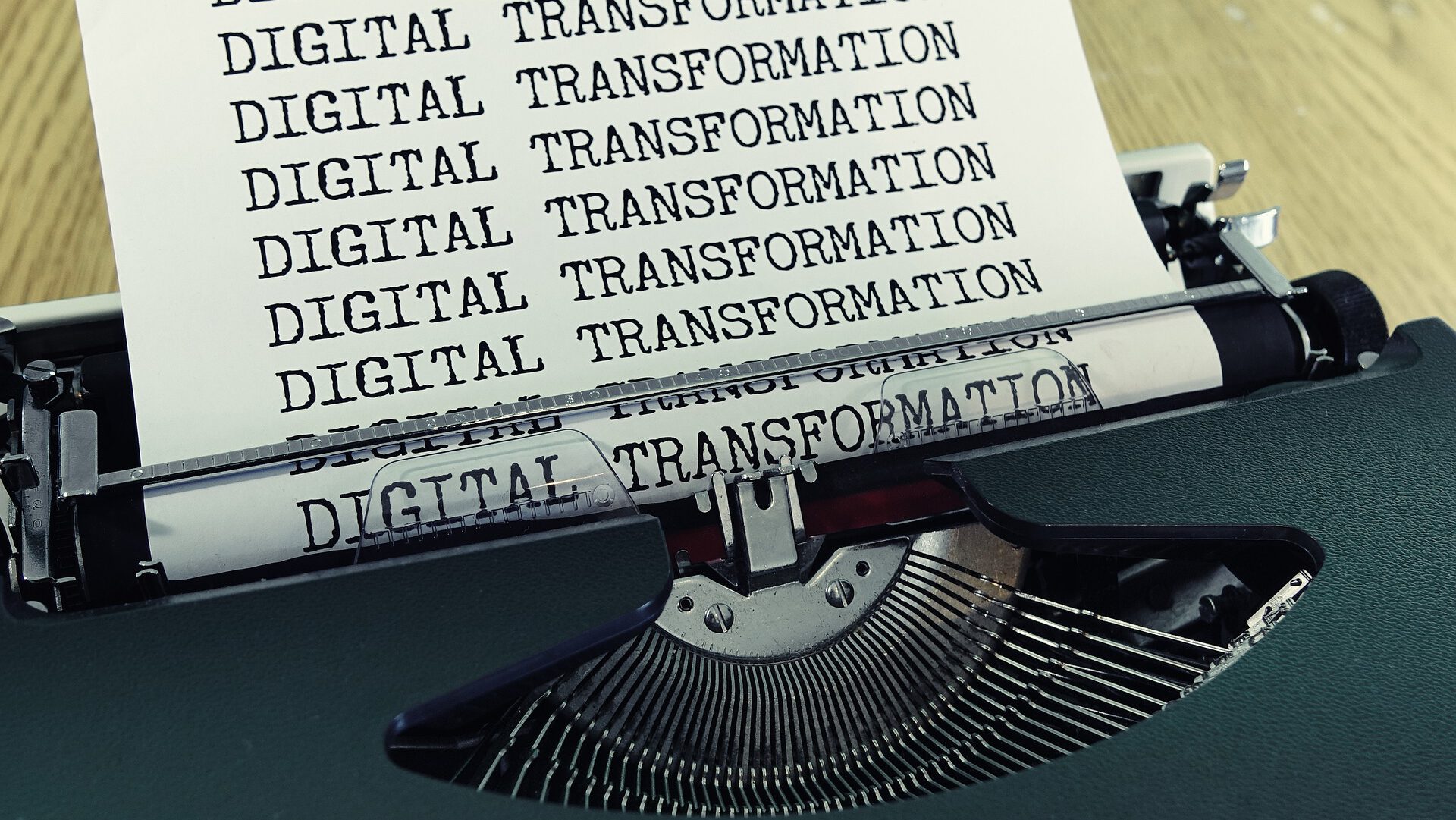 Eine Schreibmaschine, aus der ein Blatt Papier herauskommt, auf dem „Digital Transformation“ steht.
